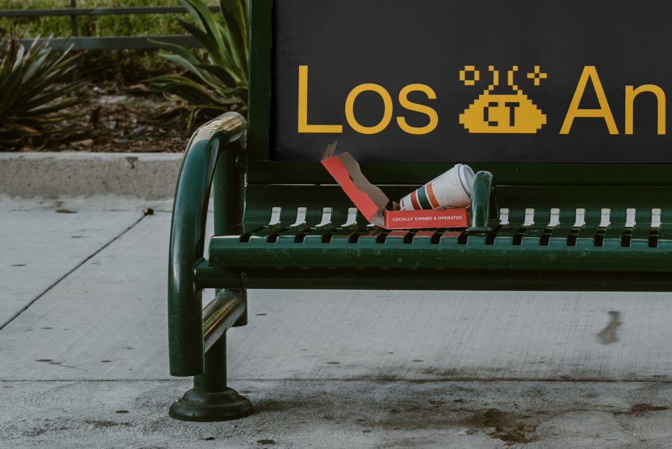 Urban bus stop bench with a spilled coffee cup and pixelated Los Angeles sign, ideal for mockup graphics.